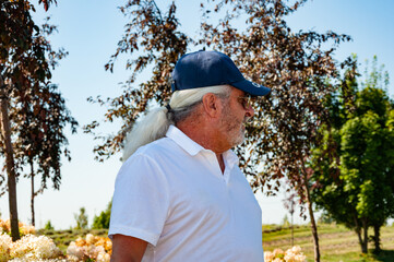 Senior old Hispanic man in summer style cap outdoor in spring nature park environment