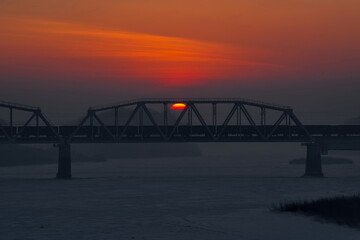 Novokuznetsk, Russia. The South of Western Siberia. The rising sun over the railway bridge on a frosty January morning.