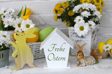 Grußkarte Frohe Ostern: Arrangement mit Osterhasen, Blumen und gefärbten Ostereiern.