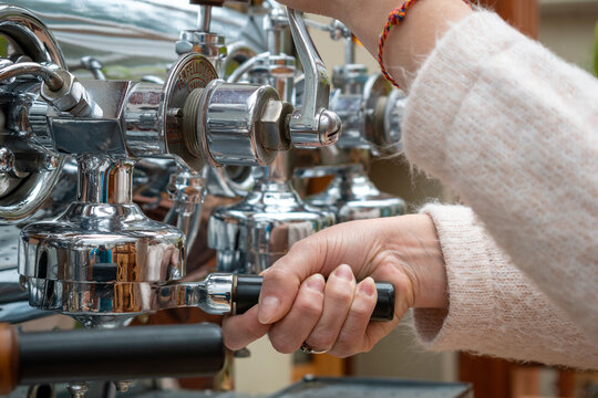 Mujer preparando café en gran máquina cafetera antigua de acero