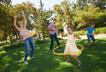Parents, kids and hula hoop in park for playing, child development and motor skills outdoor. Children, son and daughter with mom and dad in nature for leisure, family time and bonding with smile
