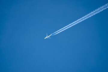 high altitude twin engine contrails (jet airplane vapour trails) across a deep blue clear sky