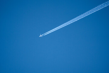 high altitude twin engine contrails (jet airplane vapour trails) across a deep blue clear sky