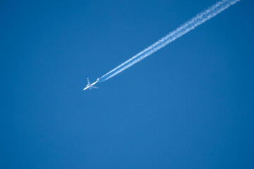 high altitude twin engine contrails (jet airplane vapour trails) across a deep blue clear sky