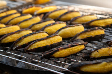 Bananas are being grilled on a charcoal grill. Let it cook slowly, street food in Thailand, Grilled bananas are a sweet and delicious dessert