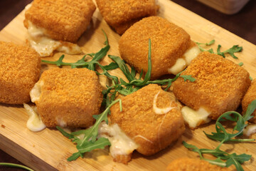 Wooden cutting board with Italian style mozzarella in carrozza. Slices of mozzarella enclosed...