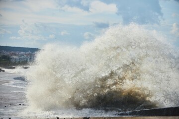 Fototapeta na wymiar A storm and splashing waves on the seashore. The impact of water on the shore