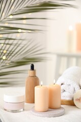 Fototapeta na wymiar Spa composition. Burning candles and personal care products on soft white surface