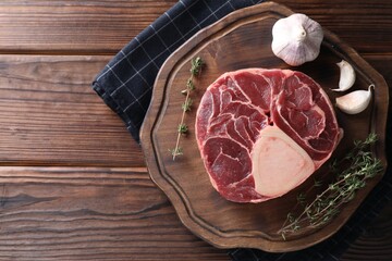 Piece of raw beef meat, thyme and garlic on wooden table, top view. Space for text