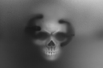 Silhouette of creepy ghost with skull behind cloth. Black and white effect
