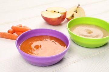Baby food. Purees of apples and carrots in bowls on white wooden table