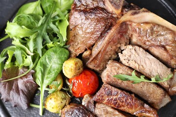 Delicious grilled beef meat, vegetables and greens on board, top view