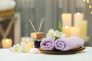 Obraz na płótnie Canvas Beautiful composition with different spa products and flowers on white towel against blurred background