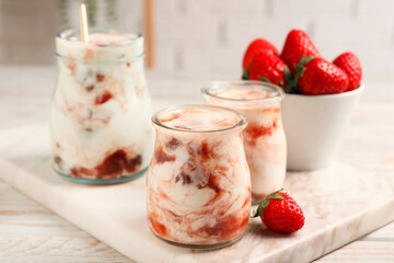 Tasty yoghurt with jam and strawberries on white wooden table, closeup