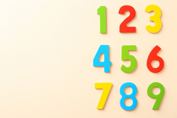 Colorful numbers on beige background, flat lay. Space for text