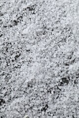 White natural salt as background, closeup view
