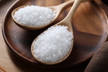 Fototapeta na wymiar Organic salt in spoons on wooden plate, closeup