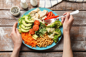 Balanced diet and healthy foods. Woman eating dinner at wooden table, top view