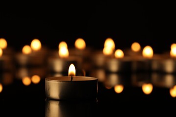 Burning candle on surface in darkness, closeup. Space for text