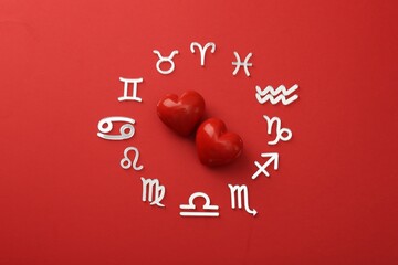 Zodiac signs and hearts on red background, flat lay