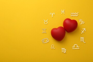 Zodiac signs and red hearts on yellow background, flat lay. Space for text