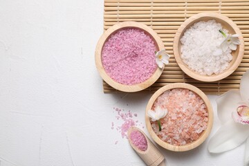 Fototapeta na wymiar Different types of sea salt and flowers on light table, flat lay. Spa products