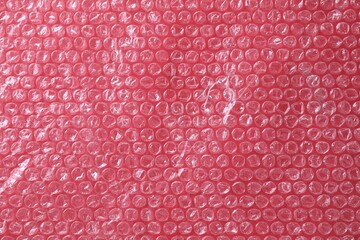 Transparent bubble wrap on red background, top view