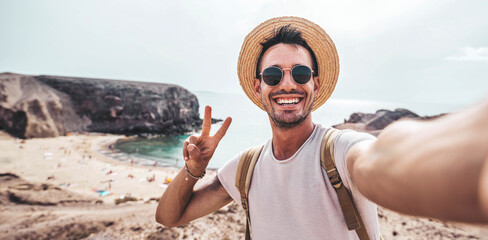 Handsome young man taking selfie with smart mobile phone at the beach - Smiling guy looking at camera outside - Summer vacation and technology concept