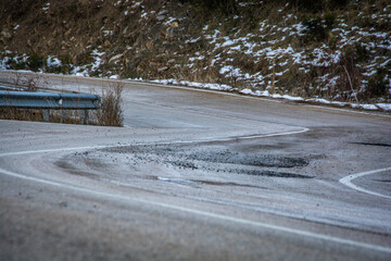 Carretera de curvas con lago de nieve, asfalto en mal estado.