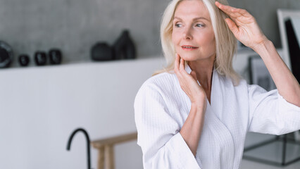 Fototapeta premium Calm woman in white bathrobe standing in bathroom at morning