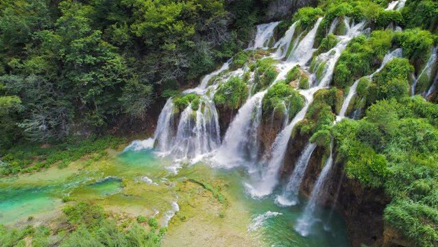 Beautiful waterfalls in summer National Park. Scenic mountain streams flow into a lake with aquamarine clear water. Summer landscape.