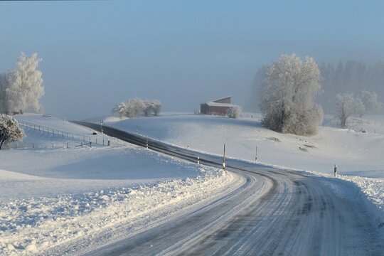 Kurvenreiche Landstraße in romantischer Winterlandschaft mit viel Schnee