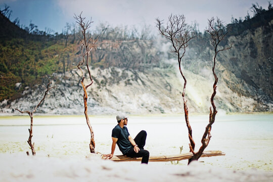 a man sitting relaxed looking at the beautiful view of the exotic Kawah Putih (White Crater)