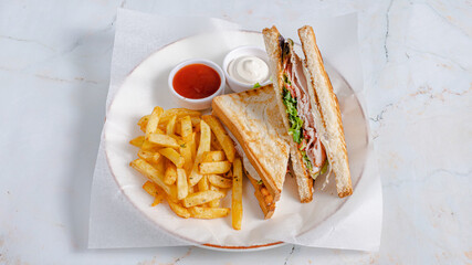 Sliced club sandwich on plate with fries