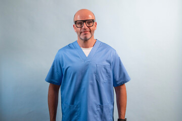 Portrait of a physiotherapist in light blue gown and glasses looking at camera in studio.