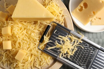 Grated, whole pieces of cheese and grater on table, top view