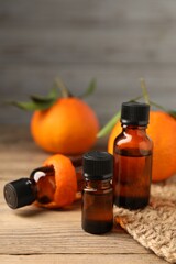 Bottles of tangerine essential oil, fresh fruit and peel on wooden table