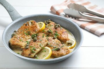 Delicious chicken piccata on white wooden table, closeup