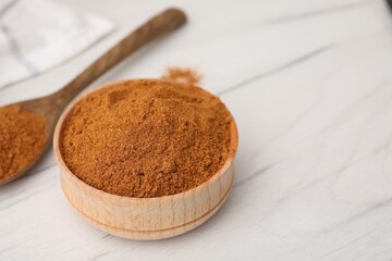 Aromatic spice. Ground red pepper in bowl and spoon on white wooden table, closeup. Space for text