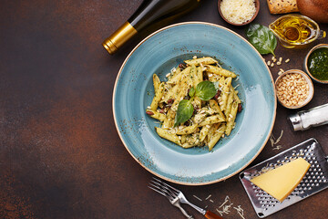 Pasta penne with chicken, pine nuts, beans, pesto sauce and basil leaves on dark concrete...