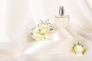 Elegant bottle of cosmetic spray, perfume on beige satin fabric with delicate roses and satin...