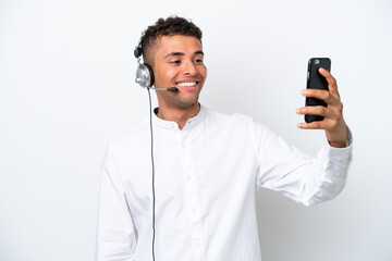 Telemarketer Brazilian man working with a headset isolated on white background making a selfie