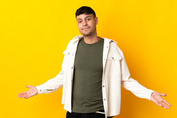 Young Colombian man isolated on yellow background happy and smiling