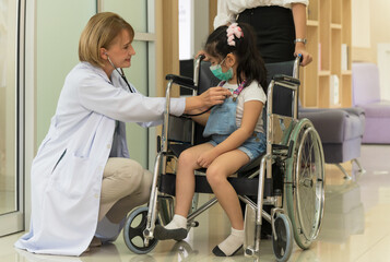 Caucasian female doctor hand using medical stethoscope for checking heartbeat rate of little girl patient in a wheelchair in hospital . Healthcare and insurance concept. - 759860007