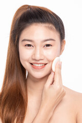 Smiling Asian woman applying foundation with a cosmetic sponge on a white background