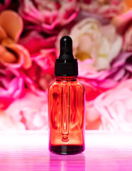 A cosmetic jar stands on a floral background with neon lighting. Liquid serum for face and body. The concept of natural youth cosmetics and perfumes. Front view