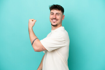 Young caucasian handsome man isolated on blue background doing strong gesture