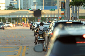 Motorcycle and cars traffic driving at intersection on American street with traffic lights in...