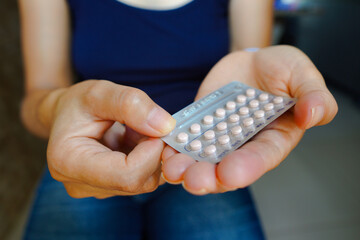 A woman holds her birth control pill. The medication is a pill that contains a combination of hormones, usually synthetic estrogen and progesterone, that inhibit ovulation.