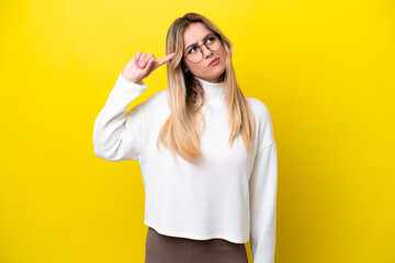 Young Uruguayan woman isolated on yellow background making the gesture of madness putting finger on...